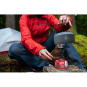 MSR Pika 1 L Teapot in use outdoors in the forest with camping stove
