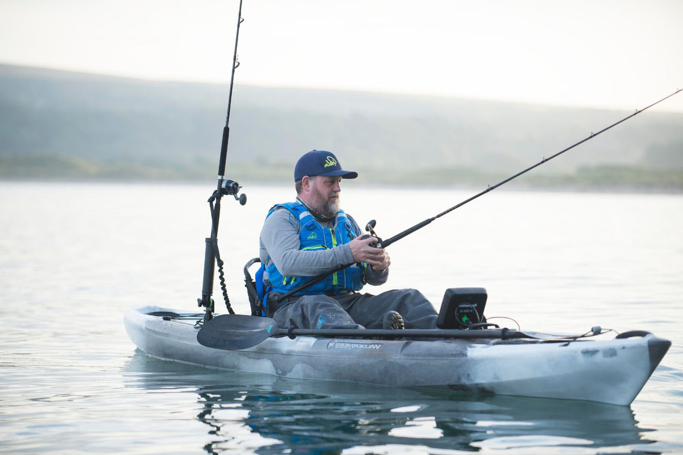 Man siting in a fishing kayak with a fishing rod in his hand